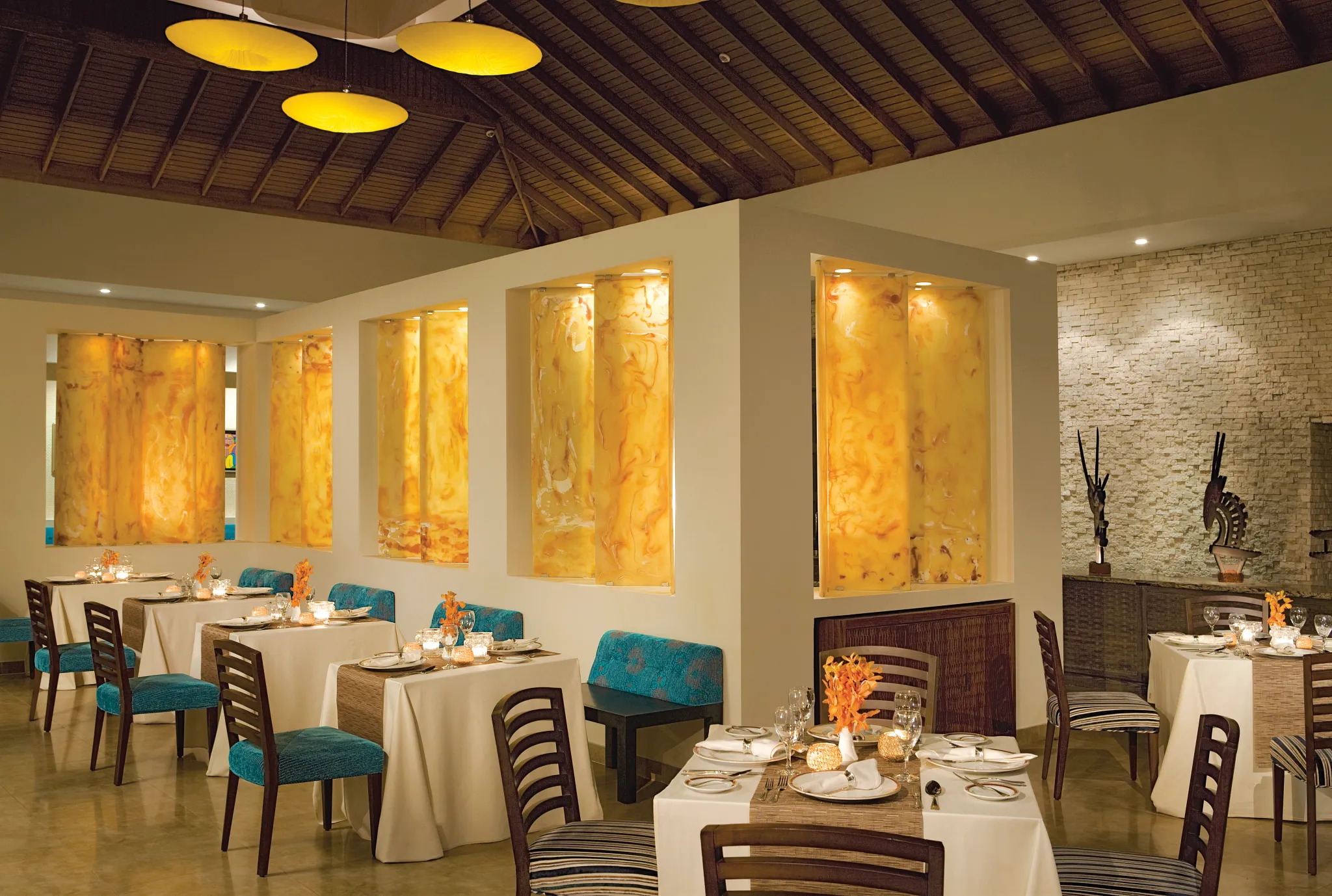 Blue Mountain Restaurant at Secrets Wild Orchid Montego Bay featuring elegant dining tables, warm amber décor, and Jamaican-Caribbean cuisine.