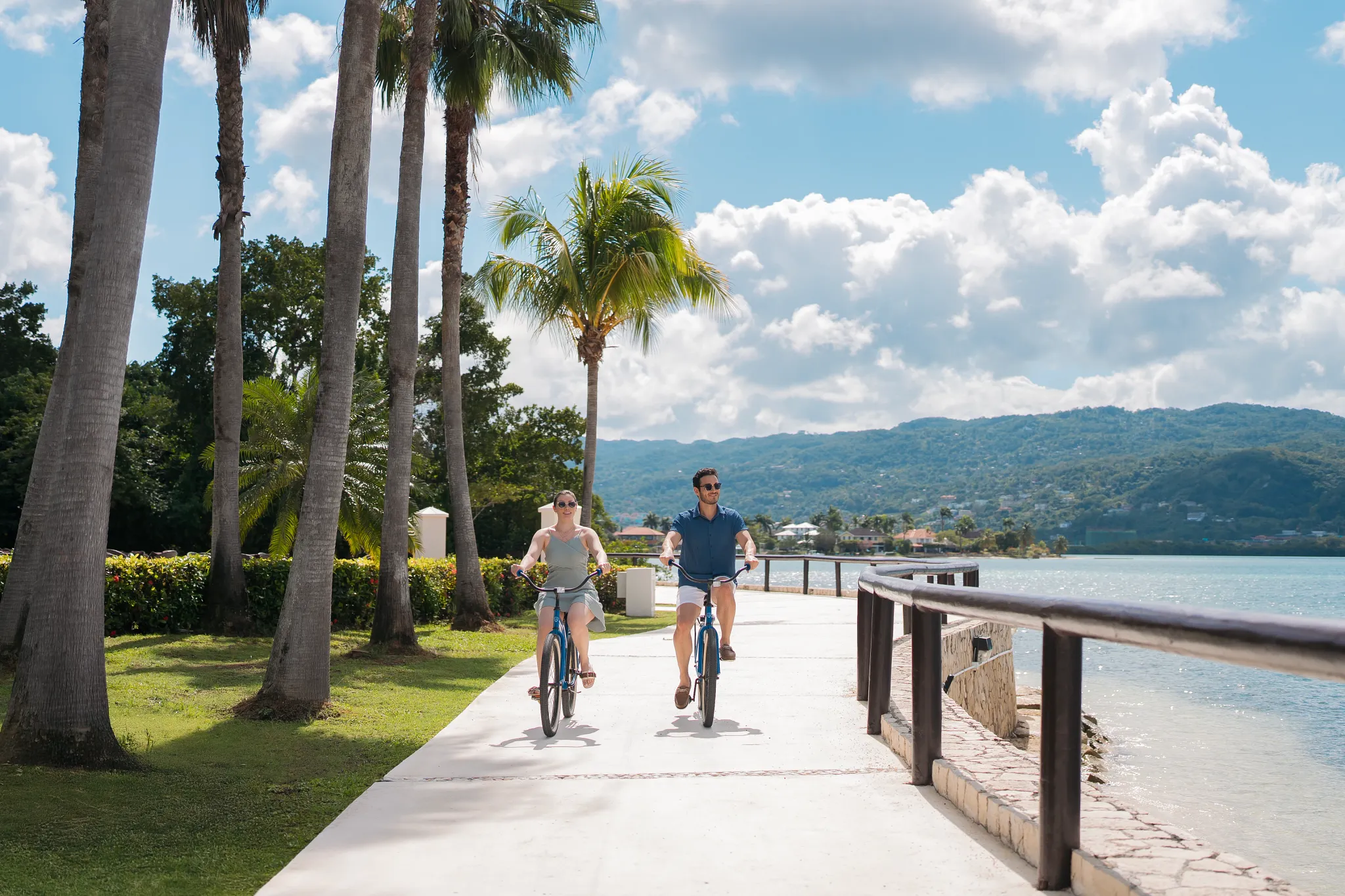 Couple riding bicycles along the oceanfront path at Secrets Wild Orchid Montego Bay in Jamaica.