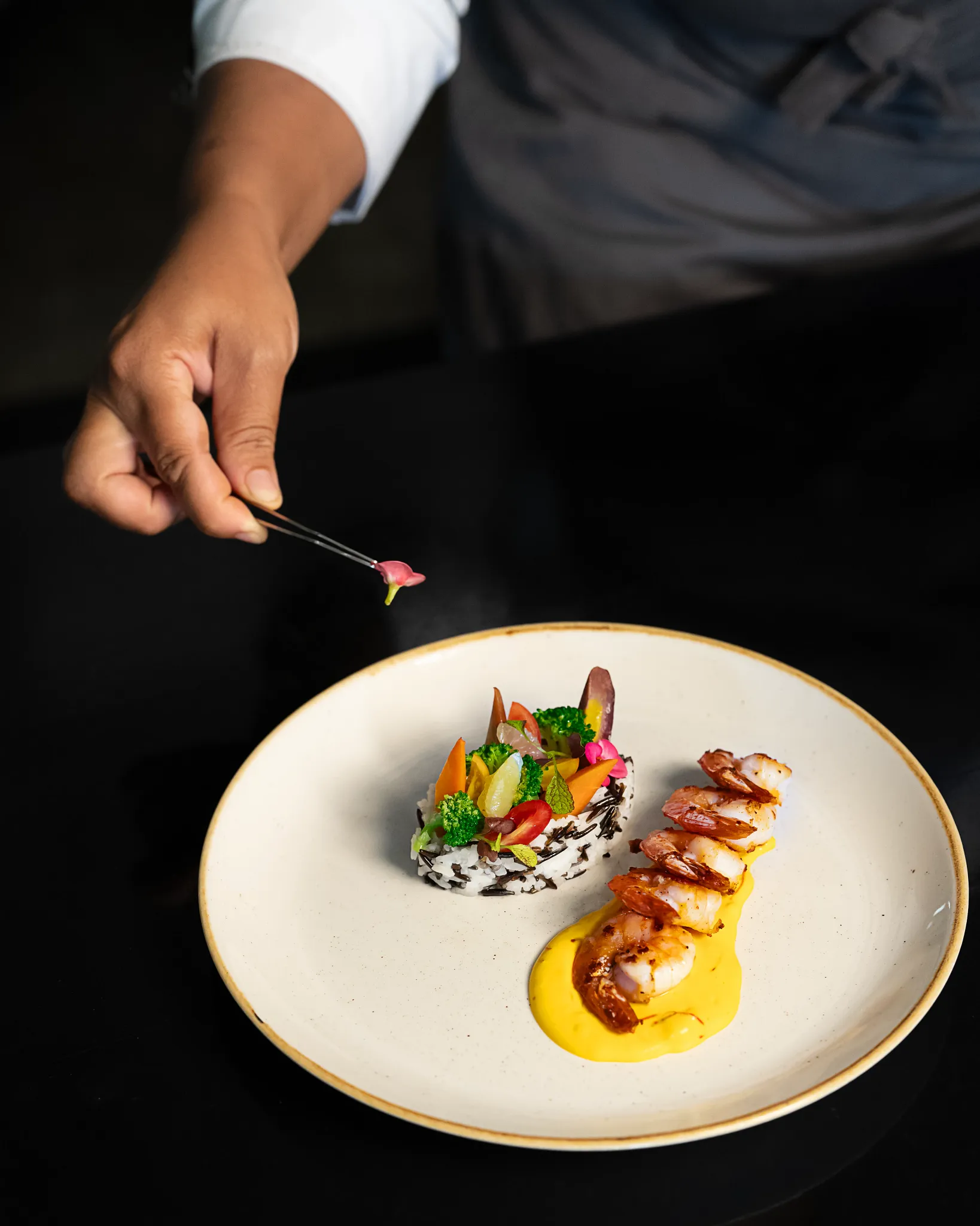 Chef delicately plating grilled shrimp and vegetables at Secrets Wild Orchid Montego Bay restaurant.