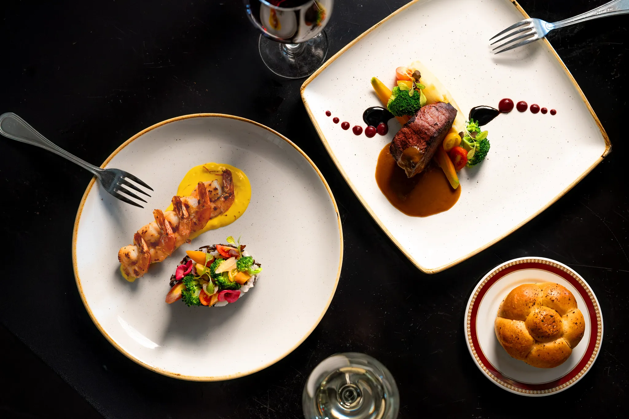 Elegant surf and turf dish with steak, shrimp, vegetables, and wine at Secrets Wild Orchid Montego Bay.